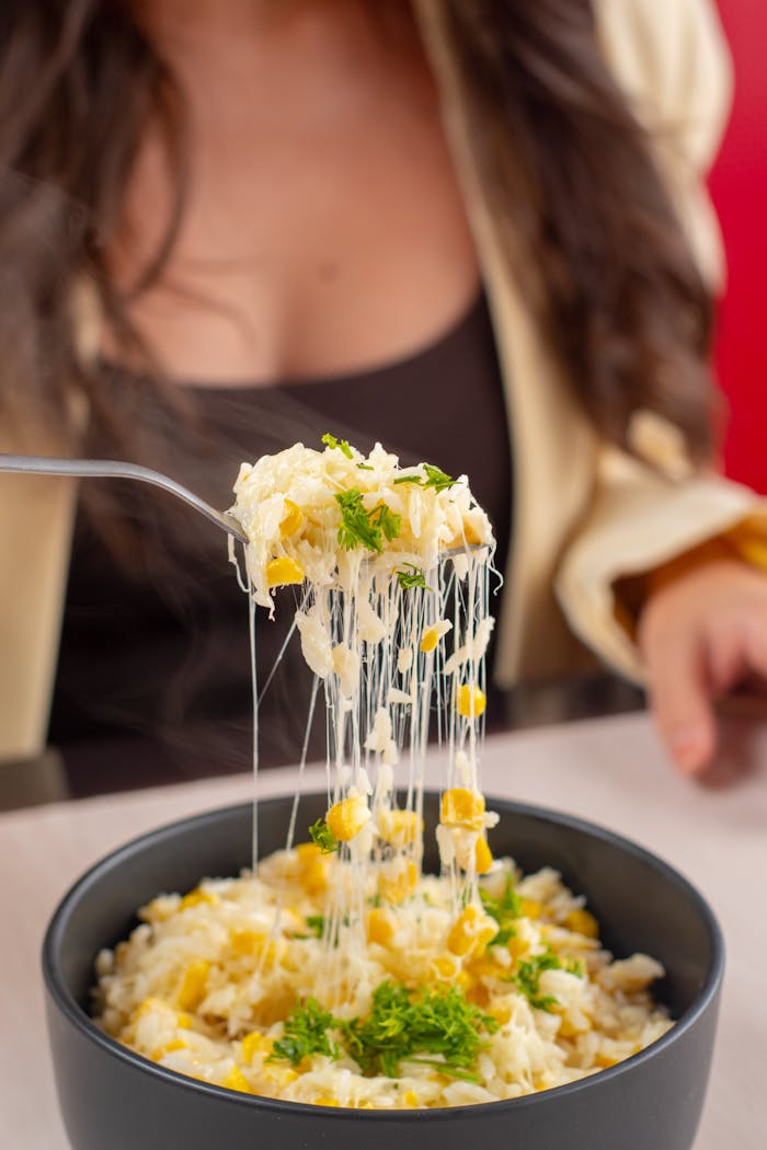 services-03 Close-up of a cheesy corn rice bowl with greenery and a person enjoying it in Guayaquil.
